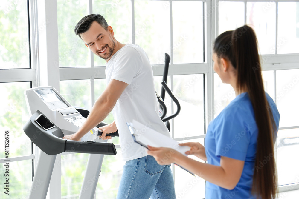 Canvas Prints Female physiotherapist working with young man on treadmill in rehabilitation center