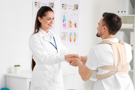 Young man with back brace and female physiotherapist in rehabilitation center