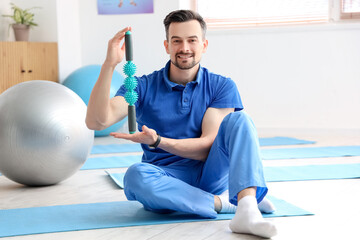 Male physiotherapist with massage roller in rehabilitation center