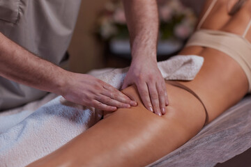 Anti-cellulite massage in the spa salon. The masseur massages the buttocks, thigh and legs....