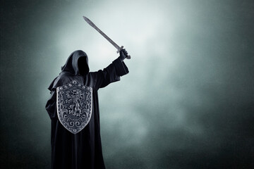 Dark knight with sword and shield over dark misty background