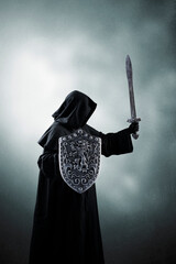 Dark knight with sword and shield over dark misty background