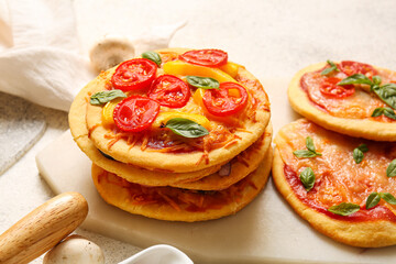 Board with different tasty mini pizzas on white background