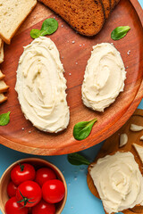 Obraz na płótnie Canvas Tasty sandwiches with cream cheese on blue background