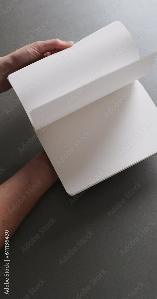 Poster vertical video of hand leafing through book with copy space on gray background in slow motion