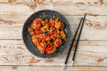 Bowl with tasty sweet and sour chicken on light wooden background