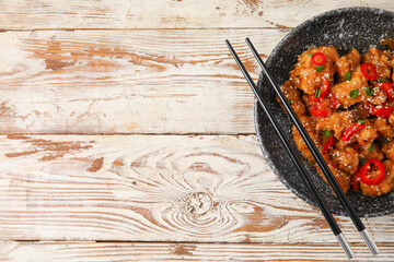 Bowl with tasty sweet and sour chicken on light wooden background