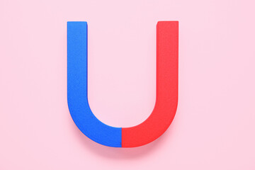 Horseshoe shaped magnet on pink background