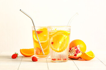 Glasses of infused water with orange slices on white tile table