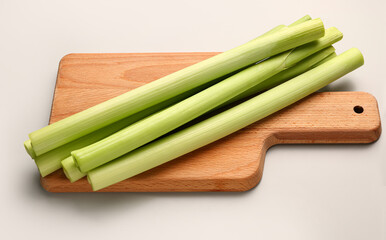 Board with fresh leeks on grey background