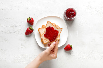 Woman holding tasty toast with strawberry jam on grunge white background - Powered by Adobe