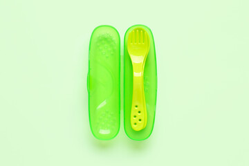 Yellow eating utensils for baby on pale green background