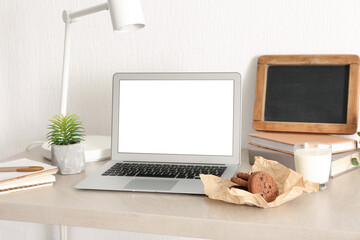 Cookies with glass of milk and laptop on table in room