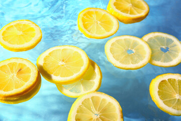 Slices of fresh lemon in water on blue background