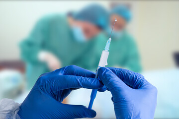 Close up man doctor holding syringe. Doctor in surgical mask and gloves preparing syringe for injection.