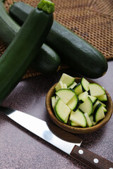 Fresh green zucchini and bowl with slices on purple background
