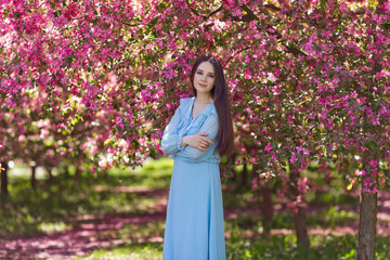 Portrait of girl in blue dress, in a pink blooming garden