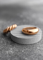 Decorative podium with beautiful golden rings on grunge grey background