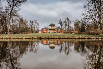 Fototapeta premium Veltrusy Castle,baroque chateau with large park,popular tourist landmark,Czech Republic.Beautiful residence in Czech countryside with representative rooms,courtyard and conical roof.Water reflection