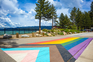Pride Flag painted on sidewalk in South Lake Tahoe for Pride Month, with view of the South East side of Lake Tahoe