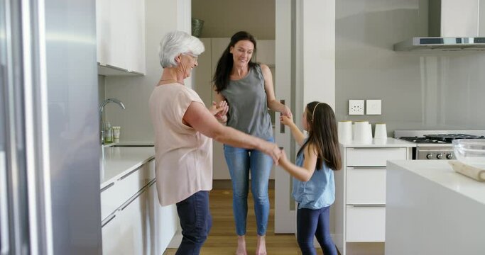 Mother, grandmother and girl dancing in kitchen with happiness, music and fun in cooking or baking. Dance, smile and happy family in apartment, generations of women play and celebrate love together.