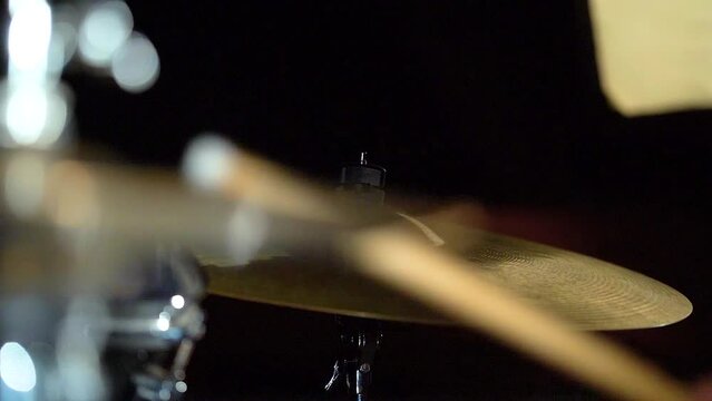 Cymbals in drum kit in frame and drummer playing performing with drumsticks.