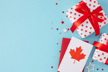 Fototapeta na wymiar Happy Victoria day celebration idea. Top view flat lay of gift boxes, blank card with red maple leaf and white red stars on light blue background with space for greeting