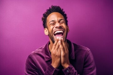 Close-up portrait photography of a satisfied boy in his 30s placing the hand over the mouth in a laughter gesture against a vibrant purple background. With generative AI technology