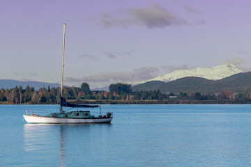 Fototapeta na wymiar Photograph of a Sail Boat on Te Anau Lake in front of snow capped mountains in the township of Te Anau in Fiordland on the South Island of New Zealand