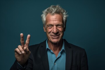 Close-up portrait photography of a satisfied mature man making a peace gesture with two fingers against a teal blue background. With generative AI technology