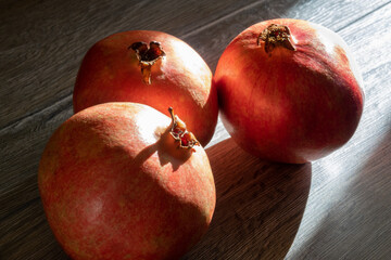 Three fresh ripe pomegranates on a gray wooden table. Close-up