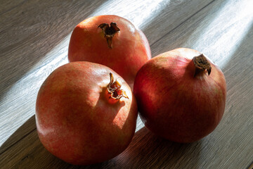 Three fresh ripe pomegranates on a gray wooden table. Close-up