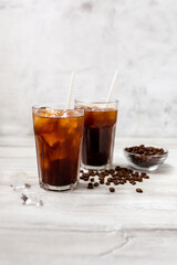 Ice coffee in a tall glass. Cold summer drink on a wooden background with copy space.