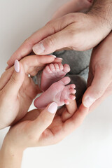 The palms of the father, the mother are holding the foot of the newborn baby on white background. Feet of the newborn on the palms of the parents. Photography of a child's toes, heels and feet.