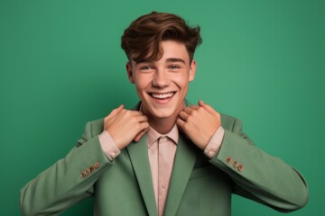 Headshot portrait photography of a joyful boy in his 20s making a heart with the hands against a pistachio green background. With generative AI technology
