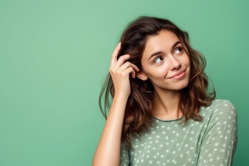 Fototapeta premium Medium shot portrait photography of a satisfied girl in her 30s scratching one's head in a gesture of confusion against a spearmint green background. With generative AI technology
