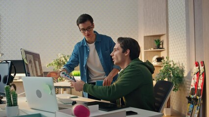 Smiling colleagues working computer in office. Eyeglasses man giving advices