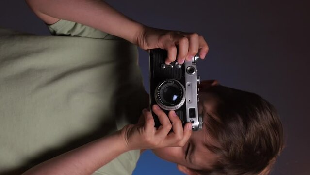 vertical video portrait of a boy taking pictures on an old vintage camera