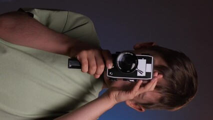 vertical video portrait of a boy shoots video on an old vintage 8mm camcorder - Powered by Adobe