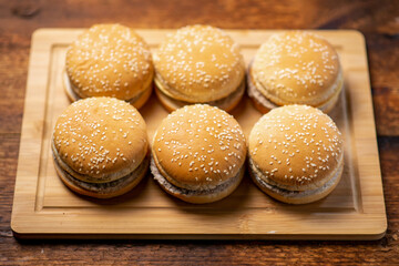 A group of cheeseburgers on a wooden background. Cooked burgers, snack.