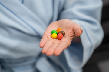 Multi-colored candies on a female palm. Small amount, diet, restriction in sweets concept.