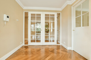 an empty room with wooden floors and white french doors leading to the entryway photo taken from inside, no people are allowed