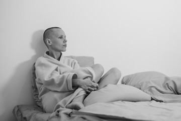 Sad depressed woman bald on the bed. Waiting for surgery, chemotherapy, stressful time. Black and...