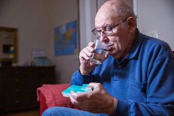 An elderly man takes his medication while at home, home healthcare