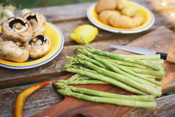 Asparagus, mushrooms, potatoes on a wooden background. Preparing to grill vegetables. Vegetarian products.