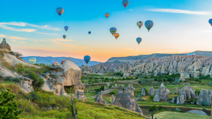 Cappadocia Turkey. Hot air balloons flying over fairy chimneys at sunrise in Cappadocia. Travel to Turkey. Touristic landmarks of Turkiye. Selective focus included. - obrazy, fototapety, plakaty