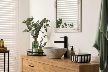 Fototapeta na wymiar Modern bathroom interior with stylish mirror, eucalyptus branches, vessel sink and wooden vanity