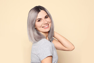 Obraz premium Portrait of smiling woman with ash hair color on beige background