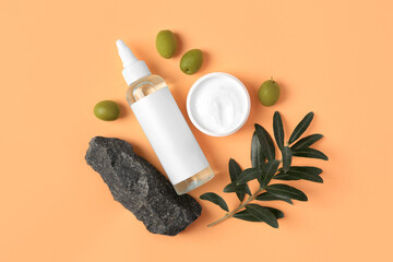 Flat lay composition with different cosmetic products and olives on pale orange background