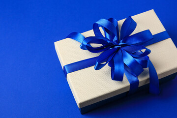 Beautiful gift box with bow on blue background